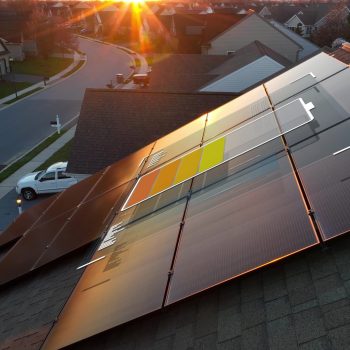 3D Battery over solar panel array on rooftop of American home during sunset. Graphic